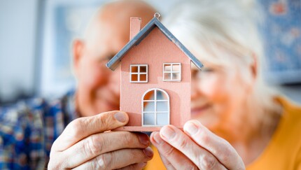 New house concept, happy senior couple holding small home model