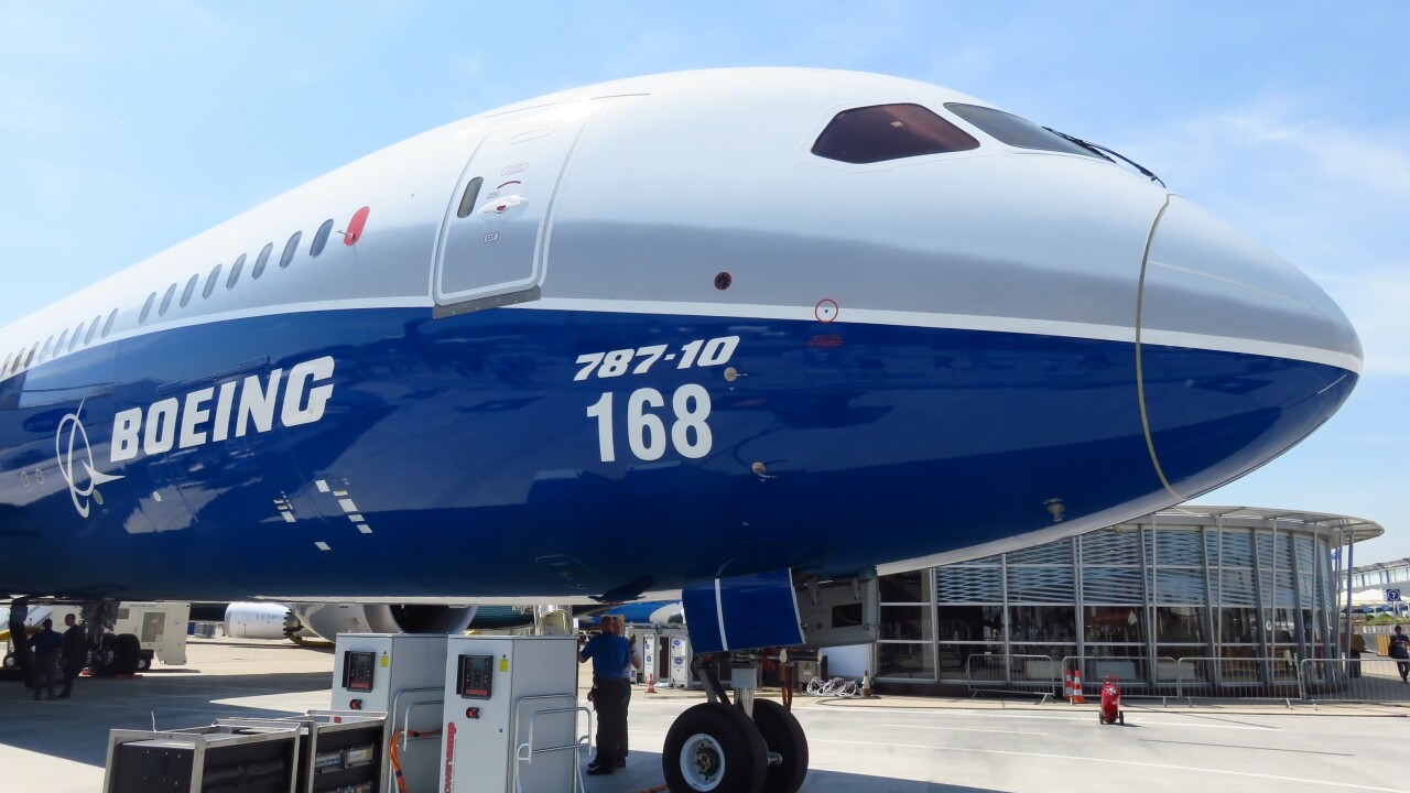 Boeing 787 plane outside of airport; a worker under the plane