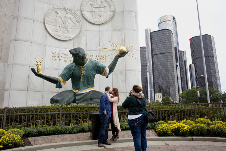 A couple kisses while standing for a photograph in front of the Spirit of Detroit monument in downtown Detroit, Michigan, U.S., on Sunday, Oct. 4, 2015.