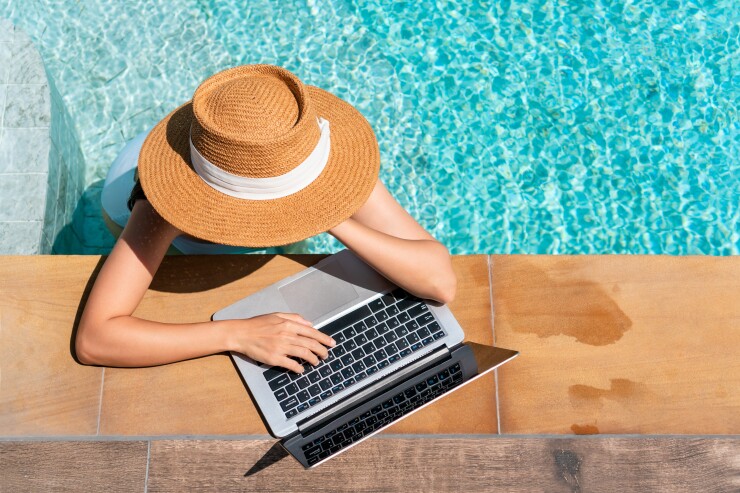 Woman working on laptop on pool deck