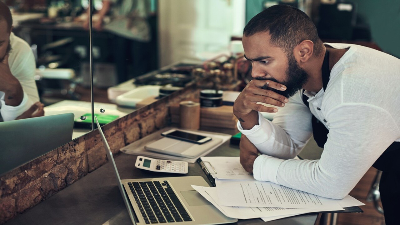 Man looking at a laptop computer on a desk.