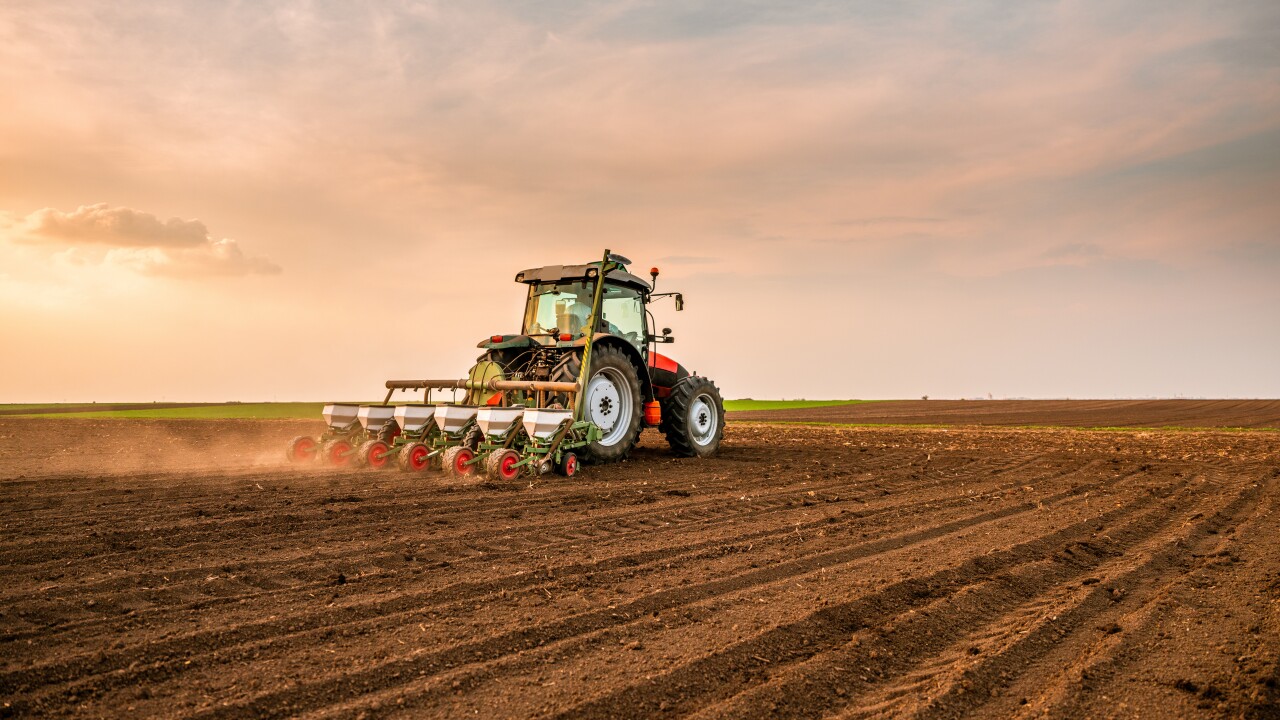 Tractor drilling seeding crops at farm field. Agricultural activity.