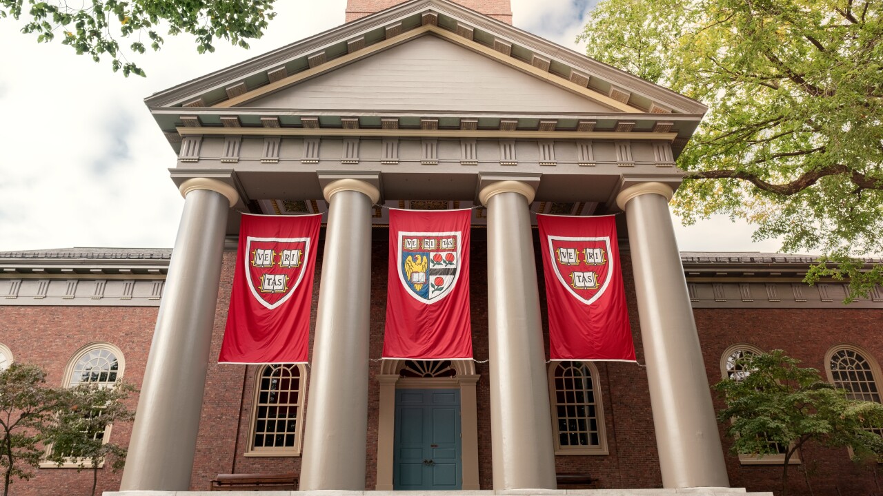 Harvard University campus: A building with four pillars and three Harvard emblem flags hanging between them.