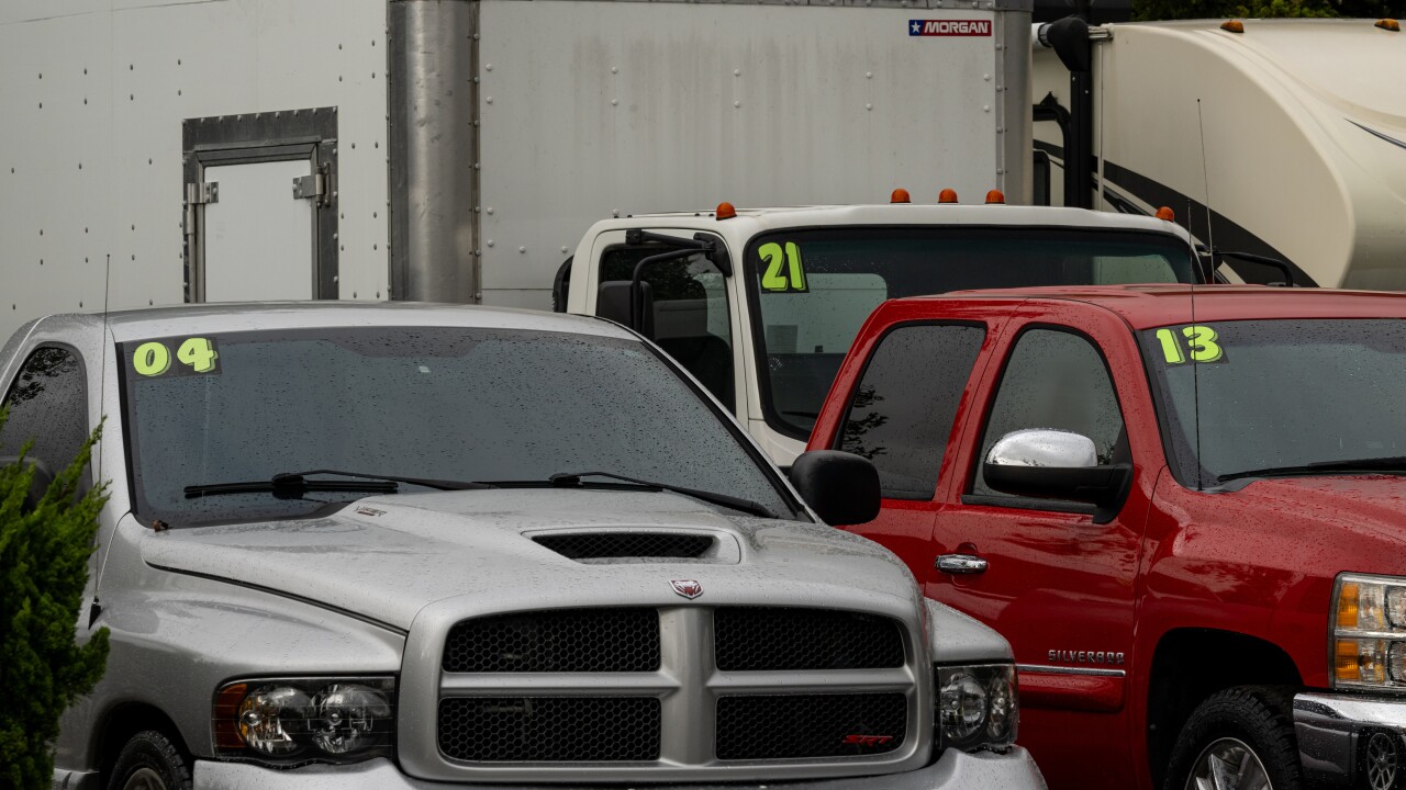 Three trucks and an RV parked in a lot.