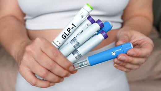 Woman holding multiple GLP-1 injection pens, weight loss and diabetes treatment concept.
