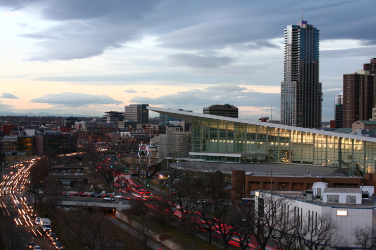 Early evening traffic passes around Jonathan Borofsky's sculpture, Dancers, in front of The Denver Performing Arts Complex and The Colorado Convention Center with the city's skyline in the background in Denver, Colorado, U.S., on Thursday, Jan. 26, 2012
