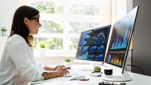 Woman sitting in front of multiple computer screens.
