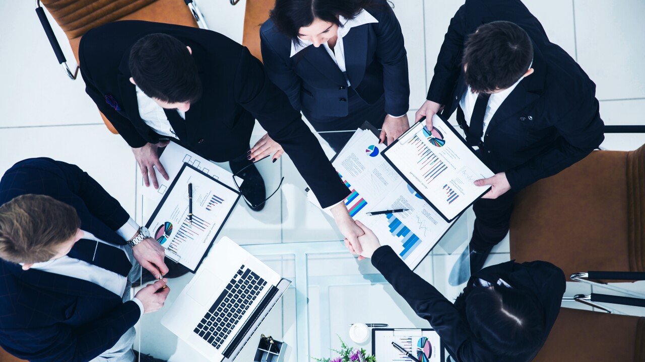 Office workers shaking hands and working together