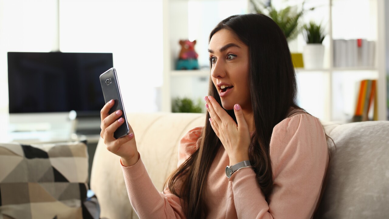 Woman looking surprised holding phone