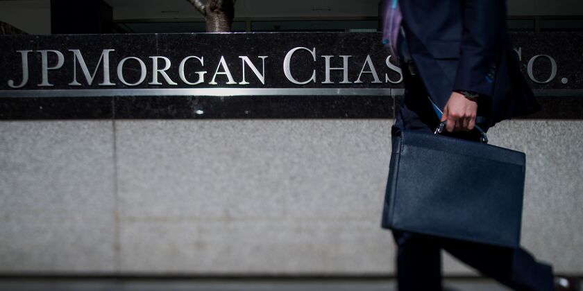 A pedestrian walks by a JPMorgan Chase sign.