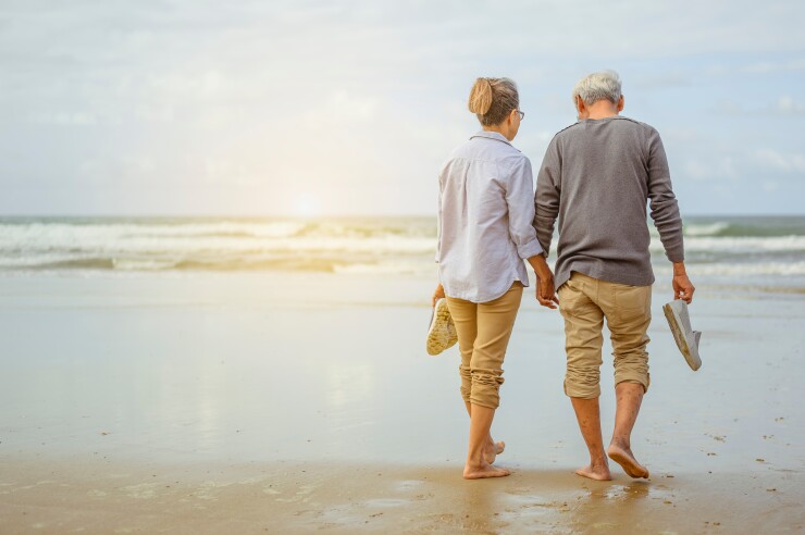 Two people walk on a beach.