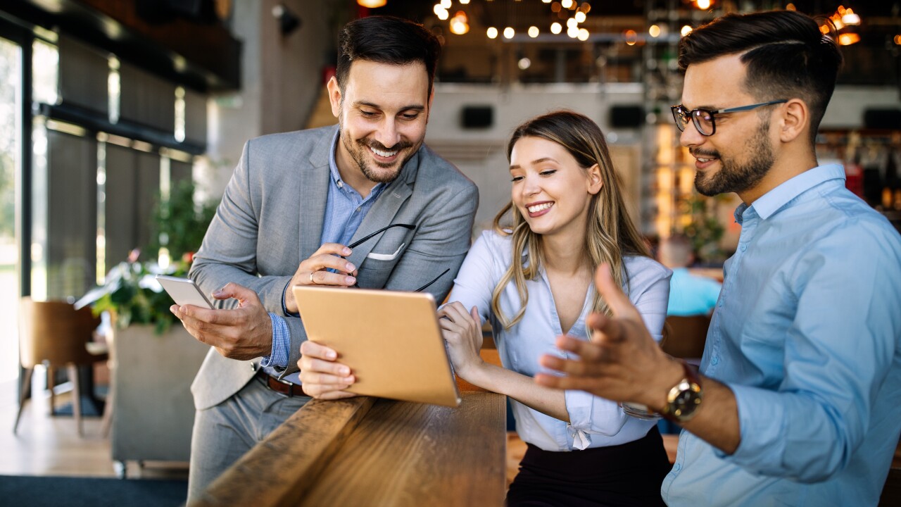 Three employees looking at tablet