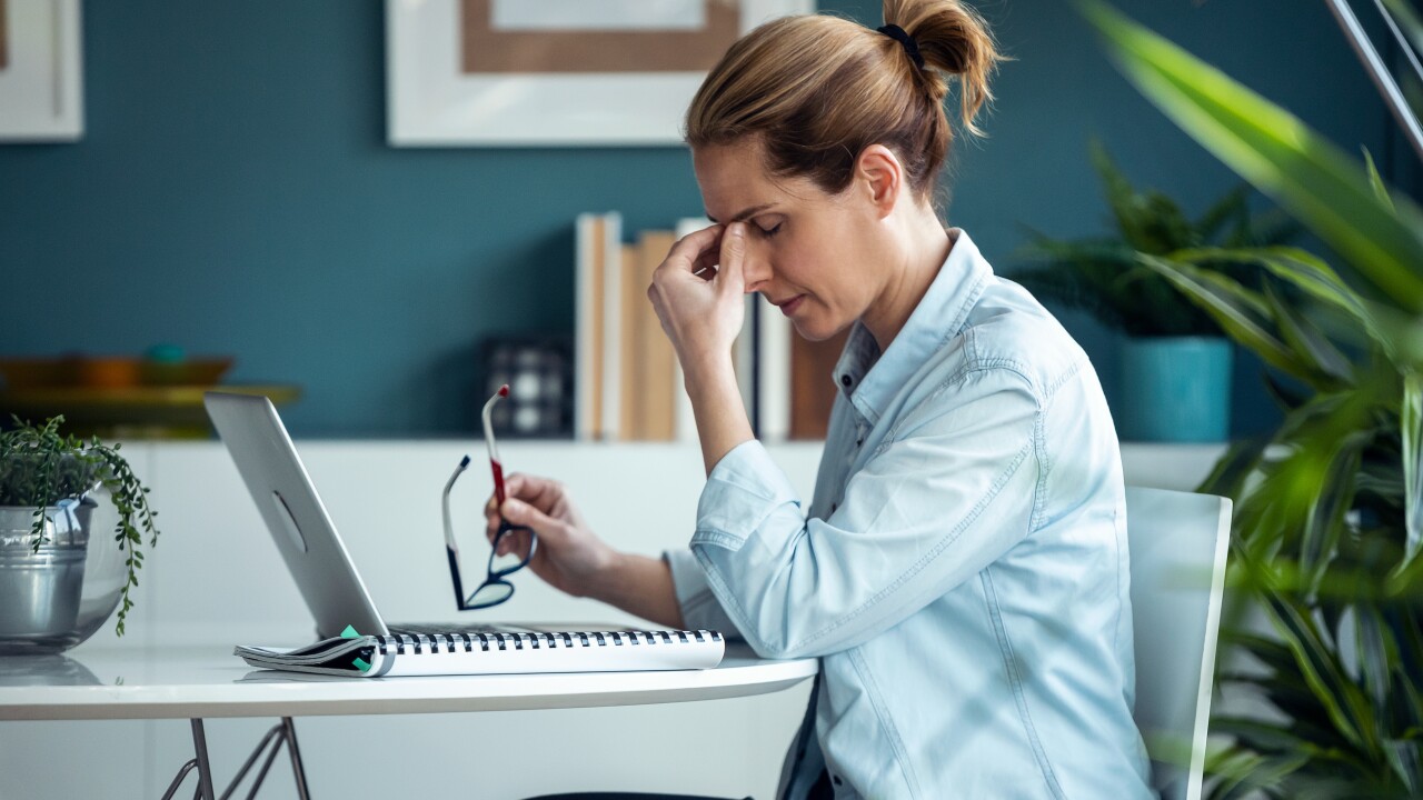 Woman sitting at her desk looking stressed
