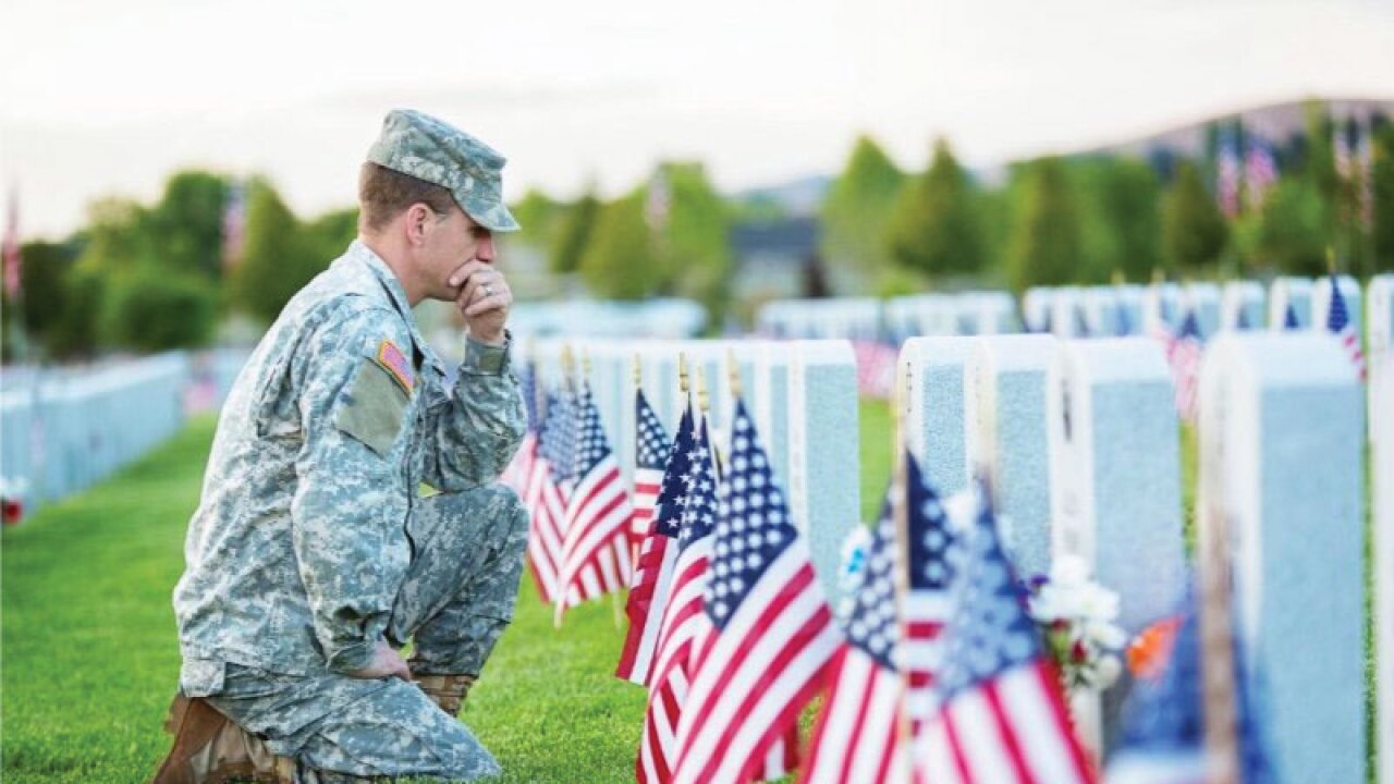 An unnamed soldier kneels before a headstone at Fort Snelling National Cemetery. Richfield-Bloomington CU spearheaded an effort to restore the practice of placing flags on all 200,000 headstones there for Memorial Day 2018.