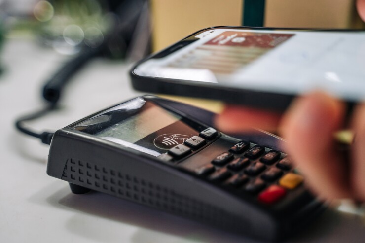 Payment for goods through a bank terminal in a contactless way using a smartphone (apple pay). Flower show in the store.