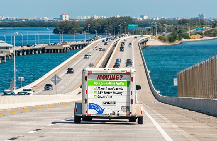A U-Haul trailer attached to a car on the interstate moves over the bridge to Tampa Bay, Florida.