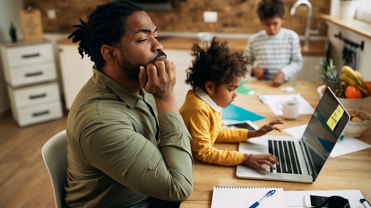 Father working at home office with child in lap concentrating