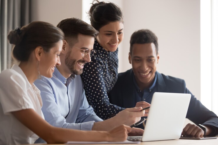 Group of employees looking at laptop, smiling