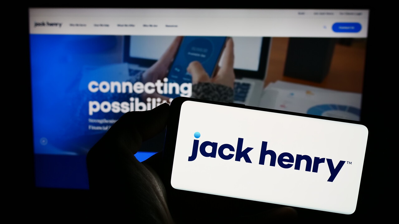 Stuttgart, Germany - 07-29-2023: Person holding smartphone with logo of US financial company Jack Henry Associates Inc. on screen in front of website. Focus on phone display.