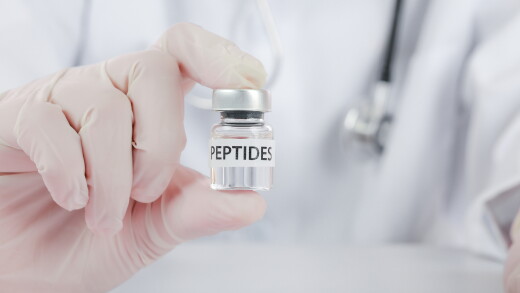 Doctor holding peptide vial inside a wellness clinic