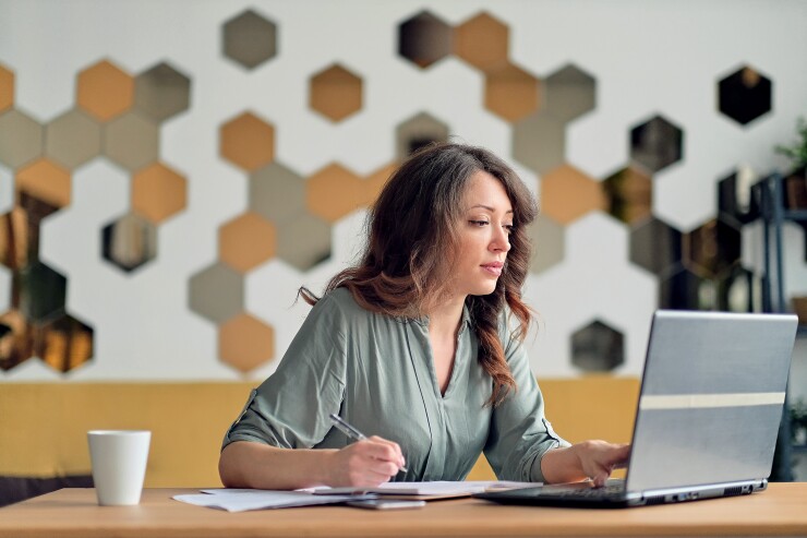 Woman looking at her computer and taking notes