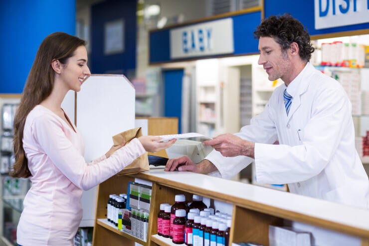 Woman standing at pharmacy counter with male pharmacist