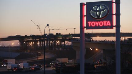 Road traffic passes along highways beyond a Toyota dealership.