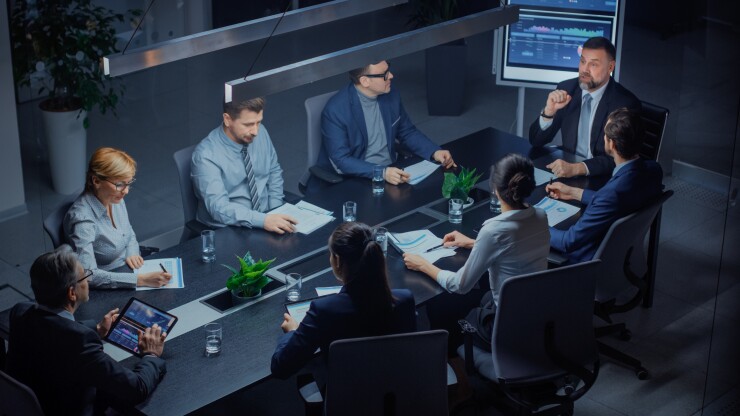 A diverse group of people sit at a conference table for a meeting.