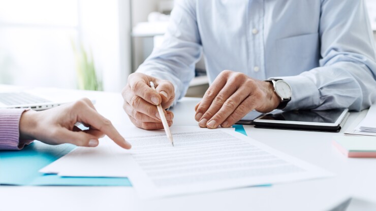Two people looking over a contract on a table.