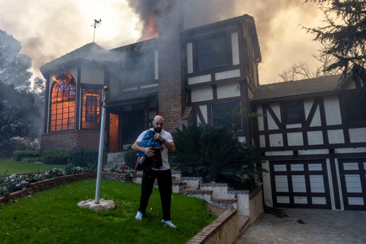 Resident carries flag outside of burning house
