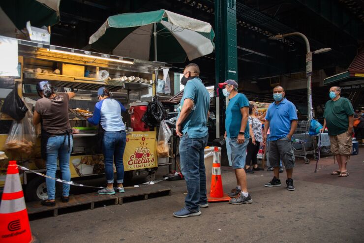 Customers stand in line outside Evelia's Tamales food cart.