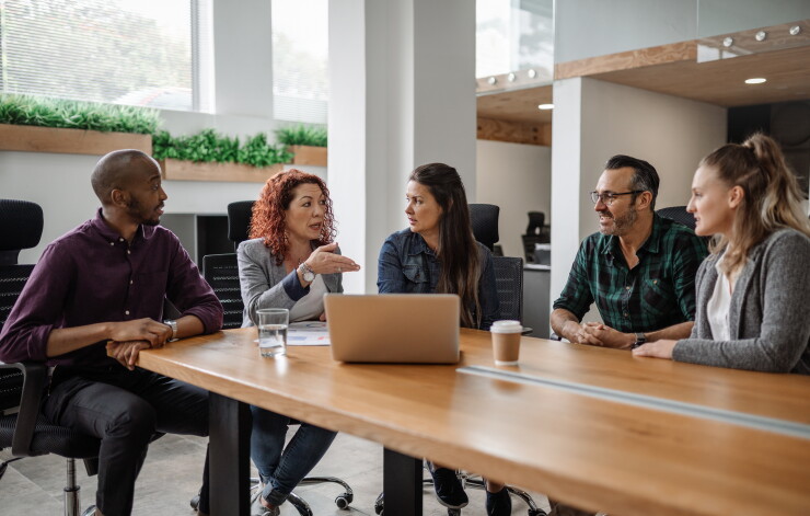 Group of employees sitting at table, talking