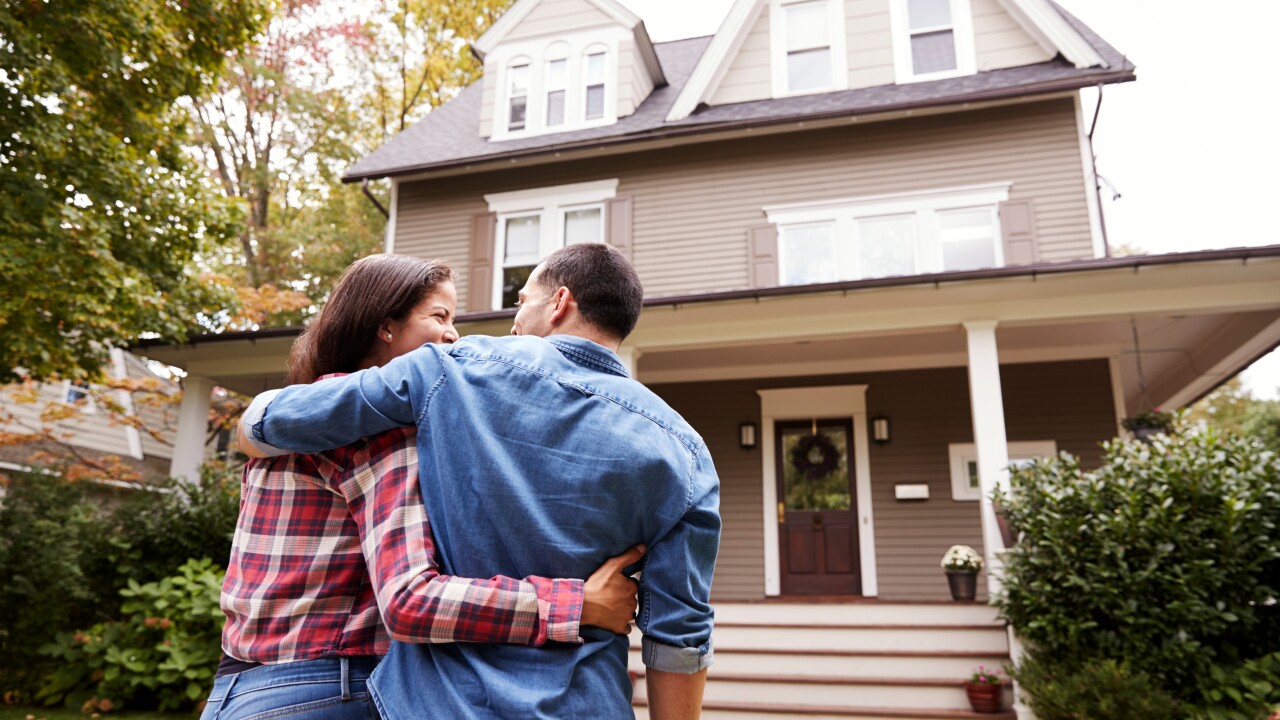Rear view of couple walking towards house.