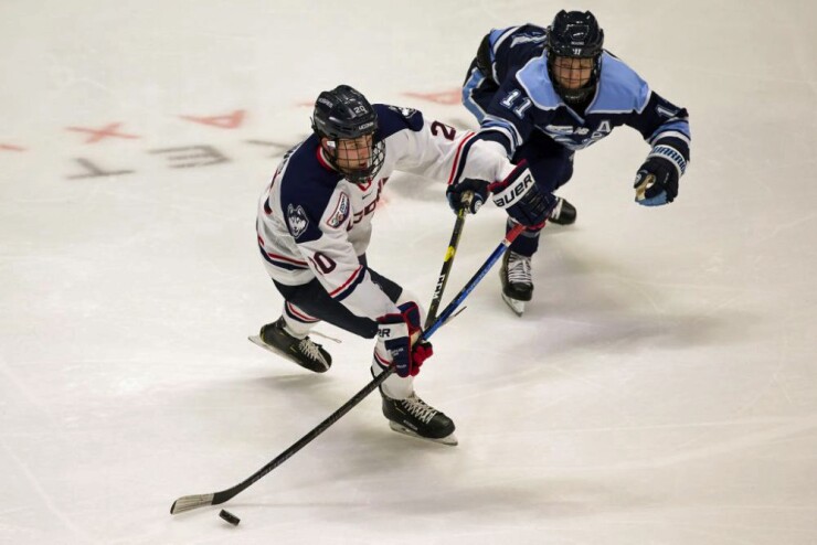 University of Connecticut hockey player Wyatt Newpower, left, and Maine's Mitchell Fossier battle during Hockey East game in Hartford.