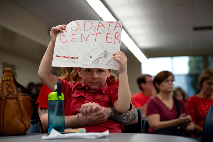 A boy holds a "No data center" sign