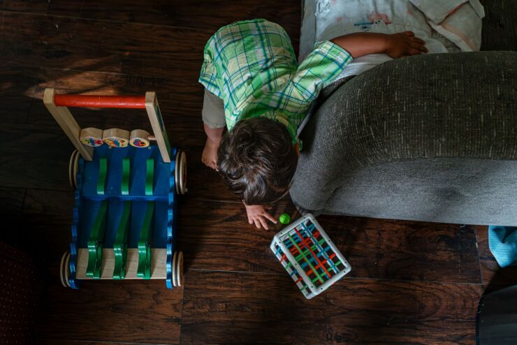 A little boy is playing with colorful, wooden toys on the living room floor.