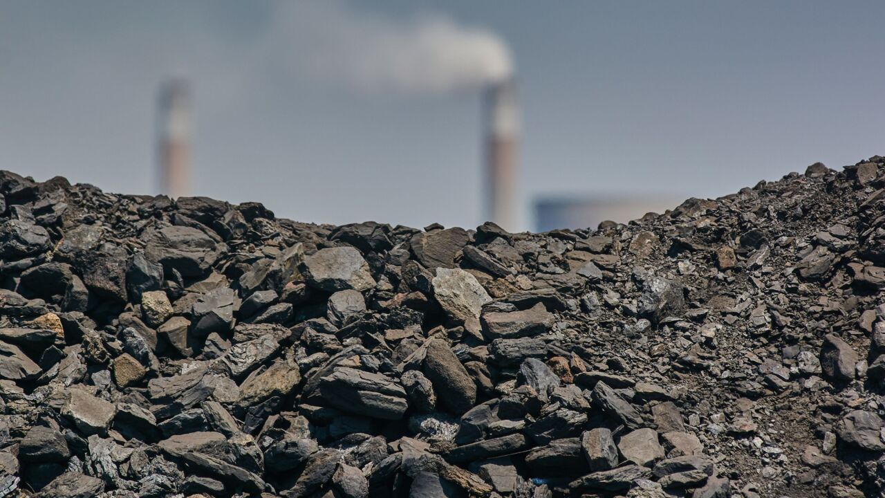 A Pile Of Coal By Smokestacks