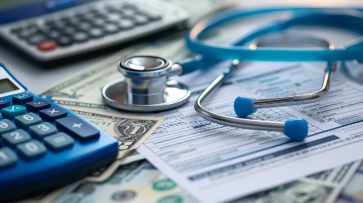 A close-up of medical expenses concept with a stethoscope, calculator, and US dollar bills on a medical billing statement, depicting the financial aspect of healthcare.