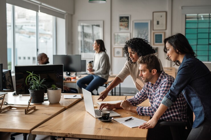 Group of young employees working in office, looking at computer