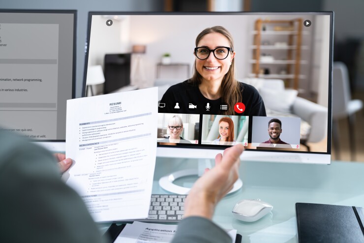 Woman interviewing virtually; person holding resume