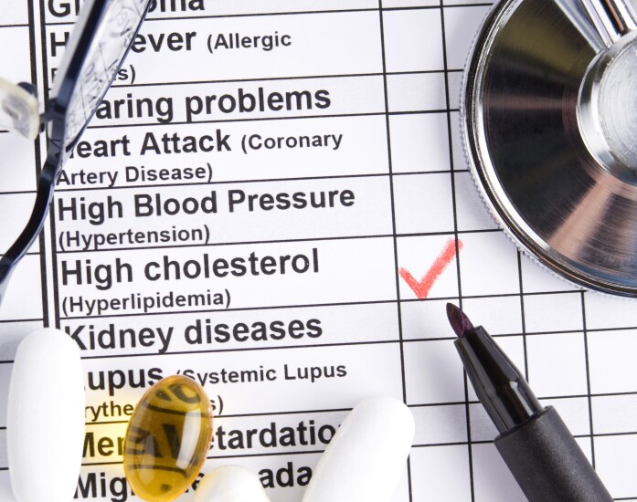 Various pills and stethoscope with high cholesterol checked