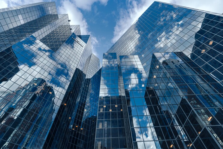 Looking up at a blue sky and several reflective buildings.