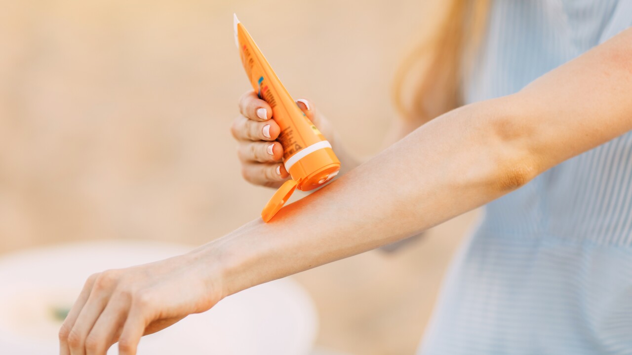 Woman putting sunscreen on arm