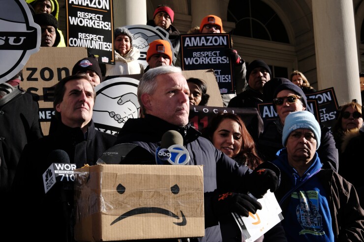 James Van Bramer, deputy leader of the New York City Council, center, prepares to rip up a brochure that says "Happy New Year from your future neighbors at Amazon" during a protest outside of City Hall in New York, U.S., on Wednesday, Jan. 30, 2019.