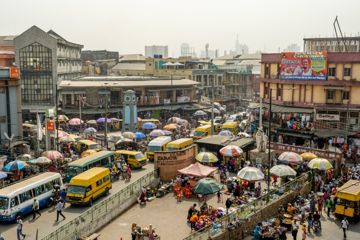 An overhead view of people, cars and market stalls on a street.