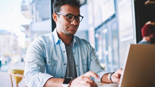 Man works on laptop from public area table