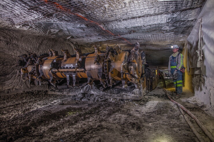 Coal miner next to large mining machine underground