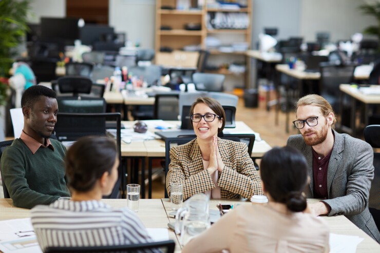 Group of employees sitting at table, collaborating