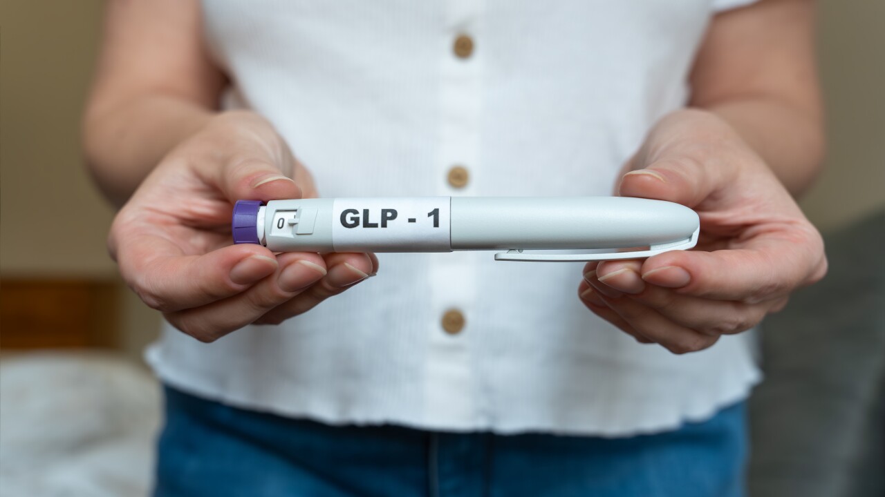 GLP-1 injection pen held by woman in front of abdomen.