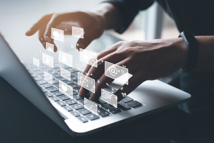 A person using a laptop with holographic images above